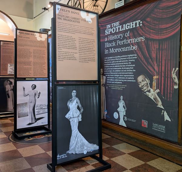 Photo of several exhibtion panels with photos of glamourous women and a man conducting an orchestra.
